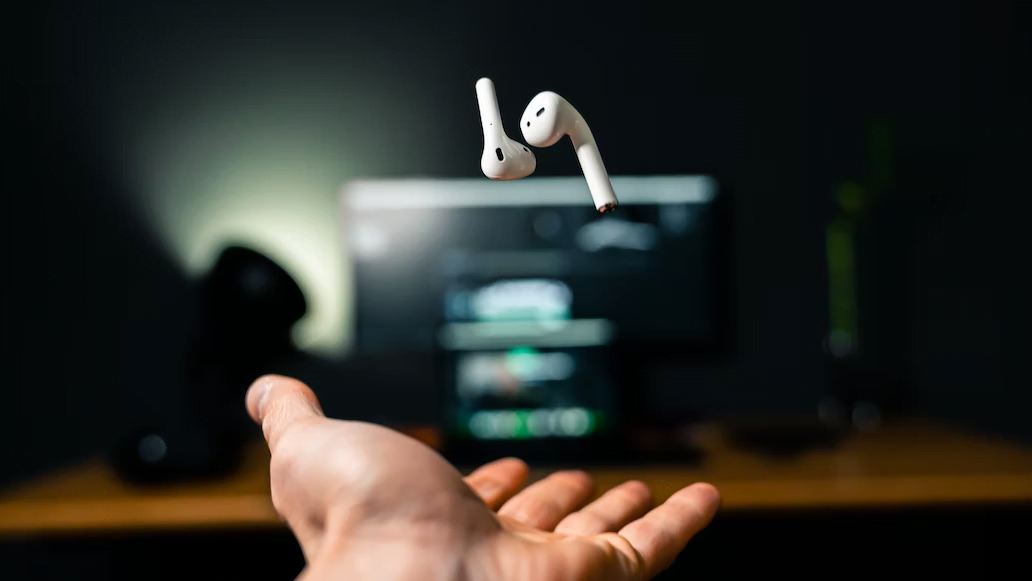 a pair of AirPods tossed by a hand